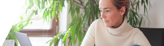 Remote and virtual assignments image of woman working from laptop with plants in background