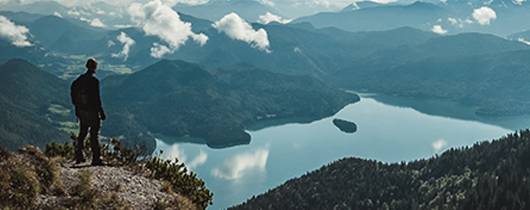 Communicating layoffs to remaining employees in 5 steps image of person on top of mountain overlooking lake